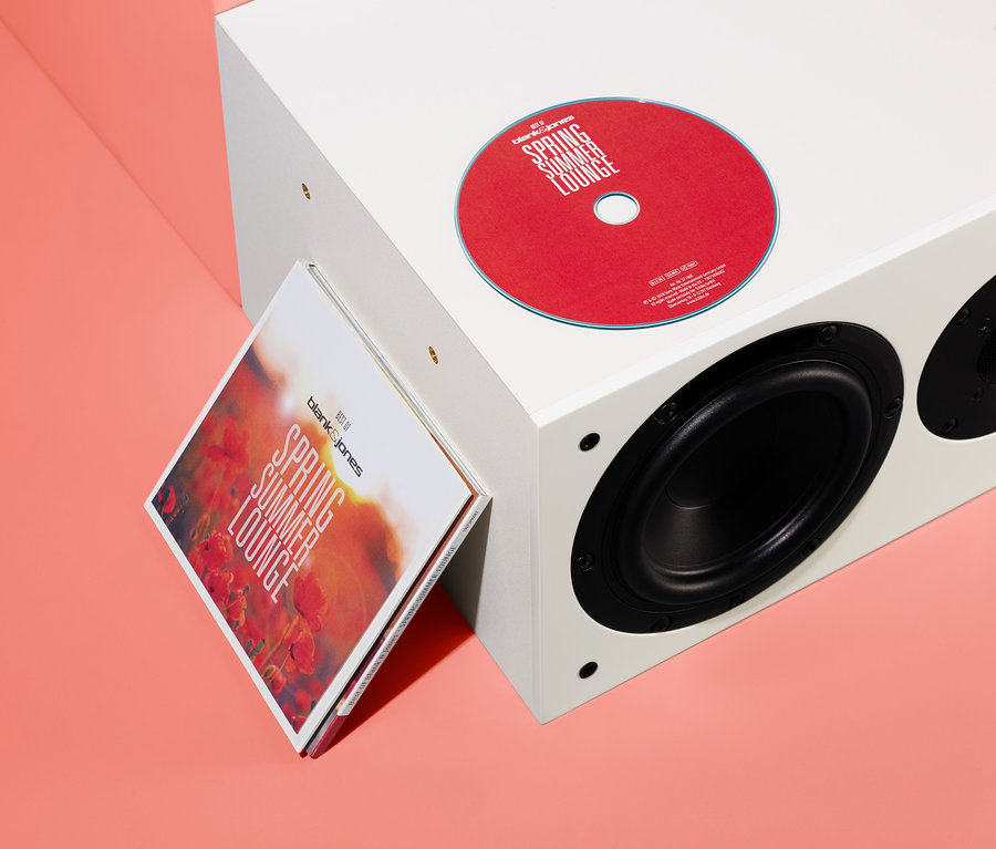 Egy piros CD és a »Best of Blank & Jones: Spring Summer Lounge« CD tokja egy fehér hangszórónak van támasztva.