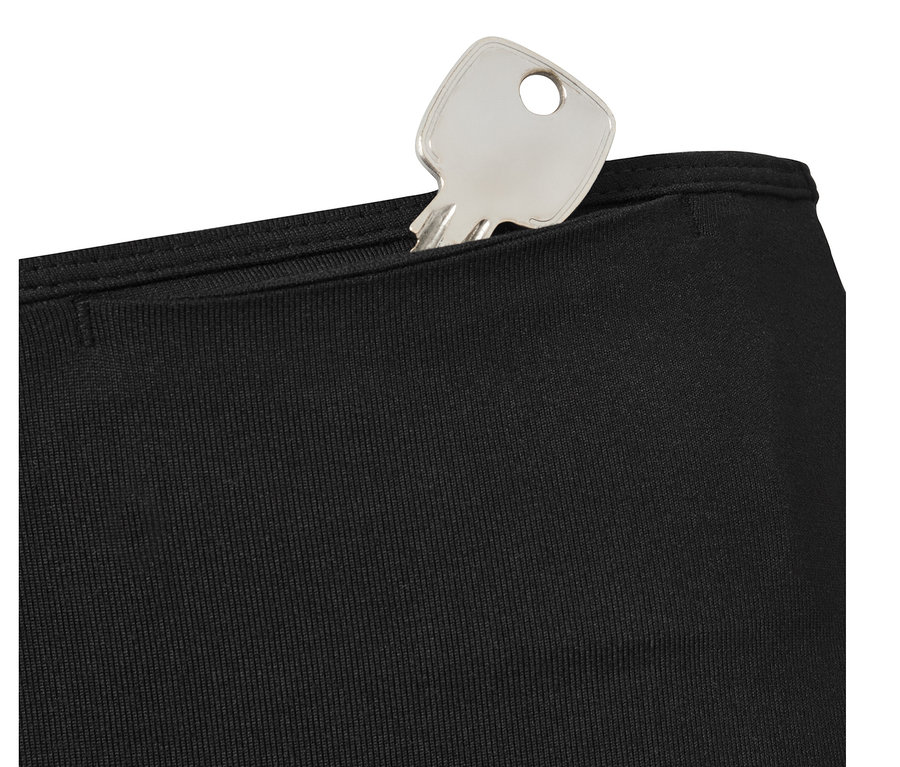 Egy ezüst színű kulcs egy fekete női sportnadrág zsebében.