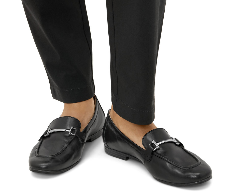 Fekete bőr női mokaszin lábakon.