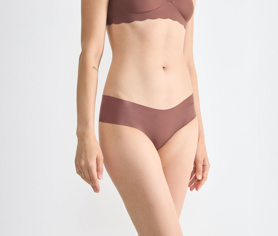 Nő visel egy barna sloggi ZERO Microfibre 2.0 hipszter alsót és egy hozzá illő, hullámos szélű melltartót.