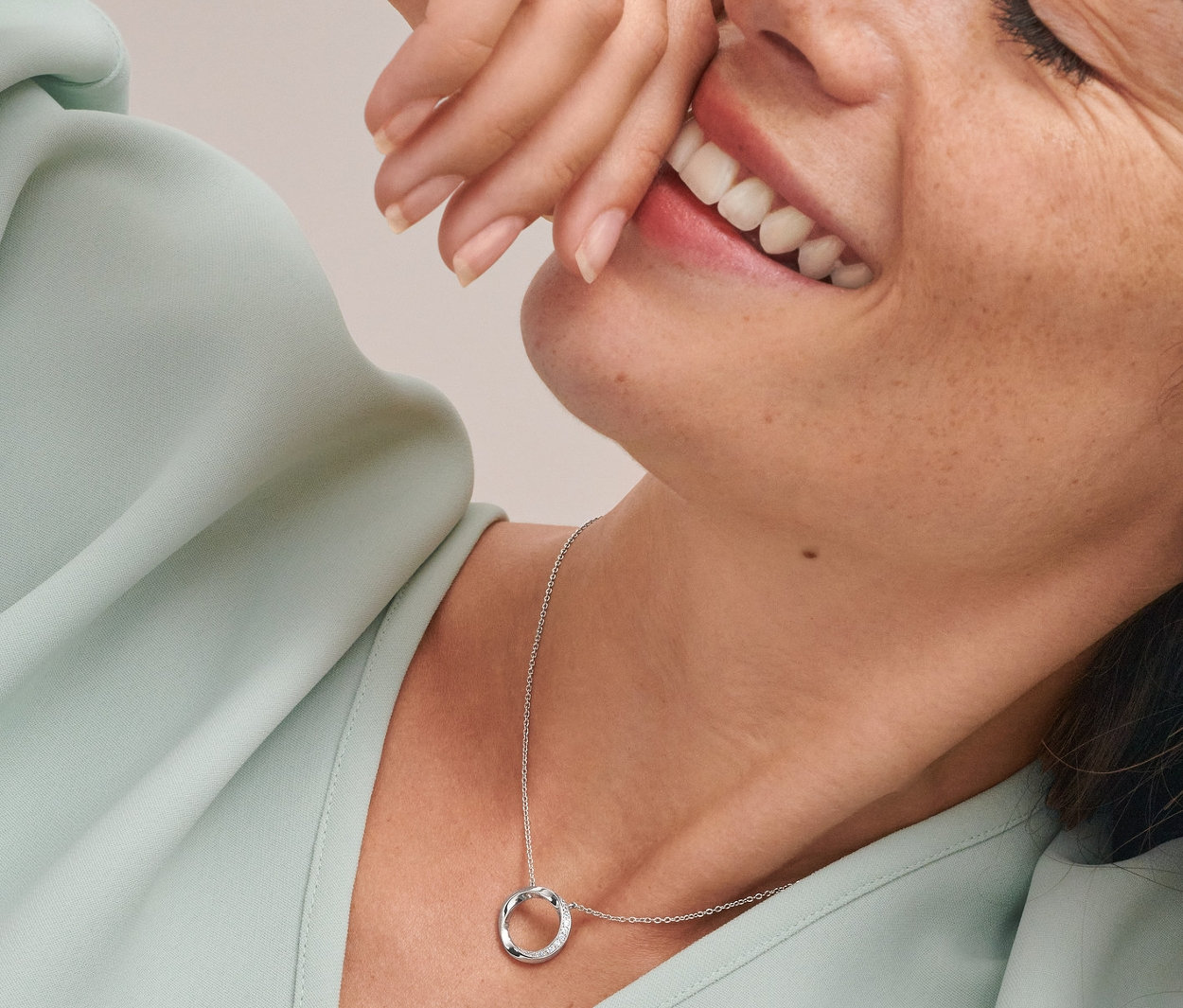 Mosolygó nő dupla, beszúrós fülbevalóval és karika medálos nyaklánccal, mindkettő ródiummal bevont 925-ös ezüstből készült.