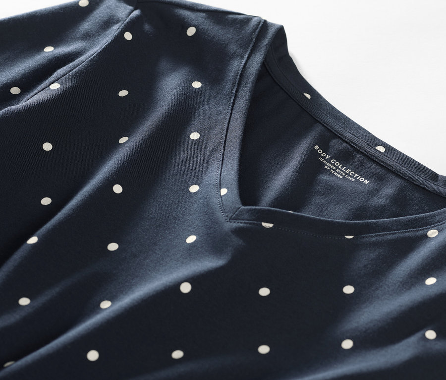 Egy sötétkék alapon fehér pöttyös hálóing részlete.