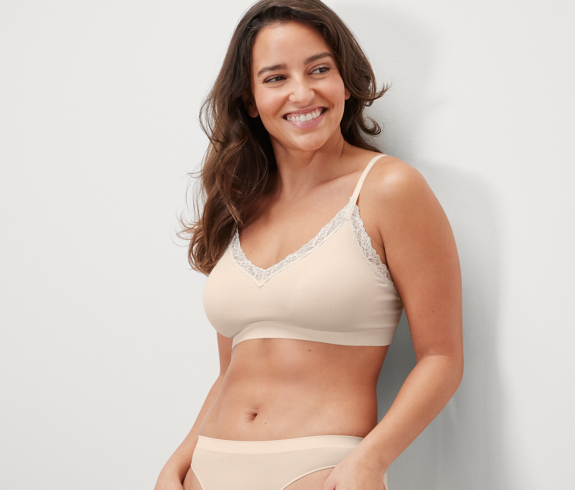 Mosolygó nő krém színű, csipkés, seamless bustiert visel.