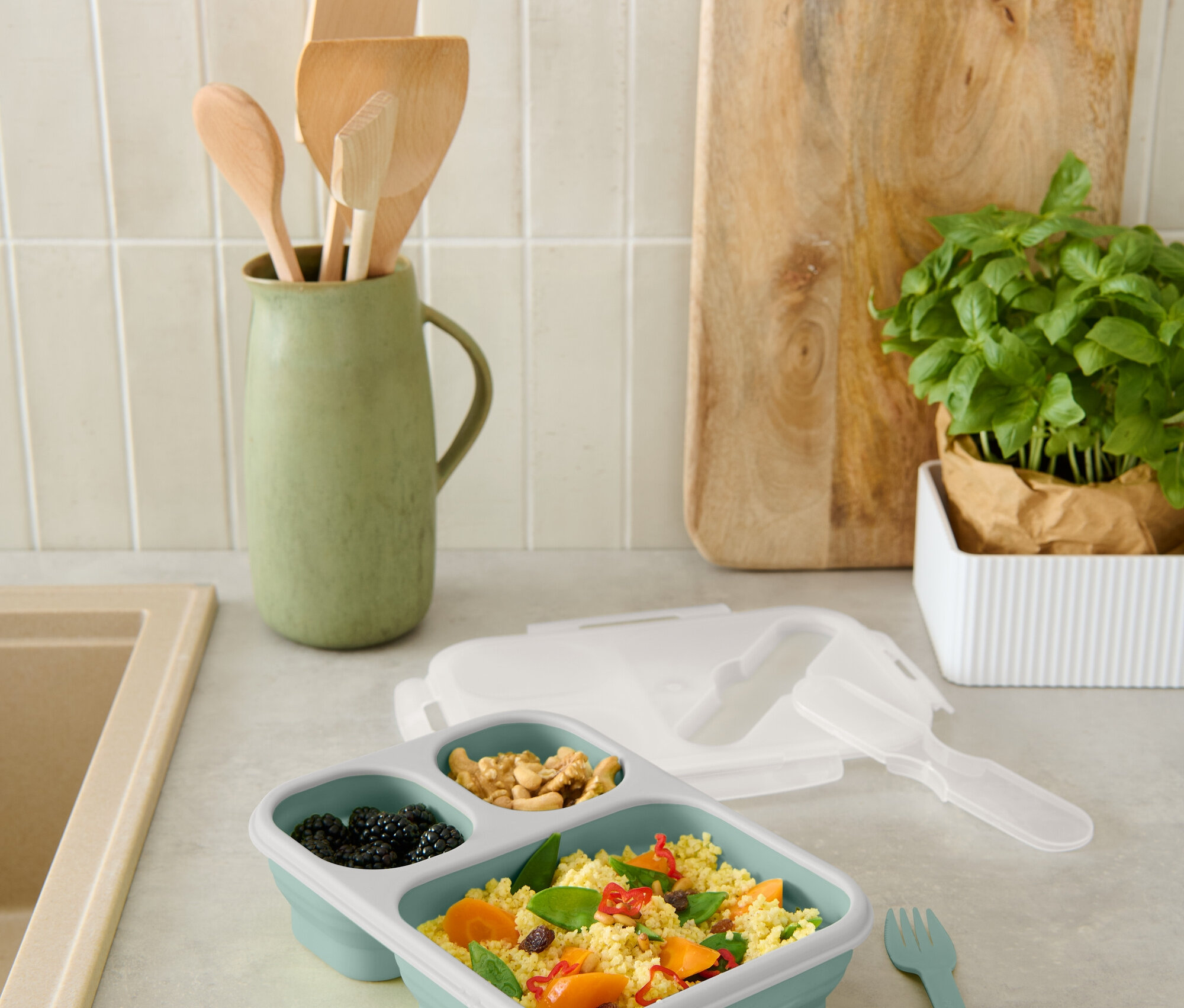 A pulton egy kék, osztott uzsonnás doboz szederrel, dióval és zöldséges kuszkusszal.