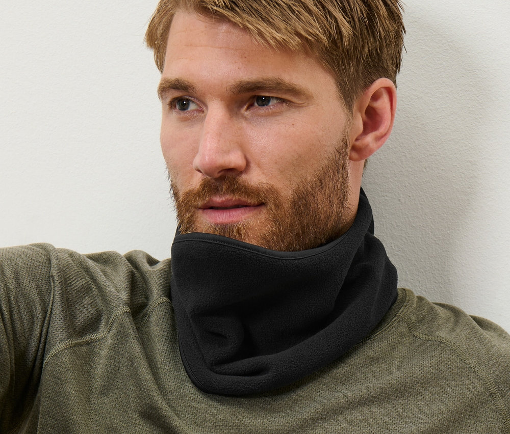 Barna hajú férfi ül, és fekete termopolár nyakvédőt visel.