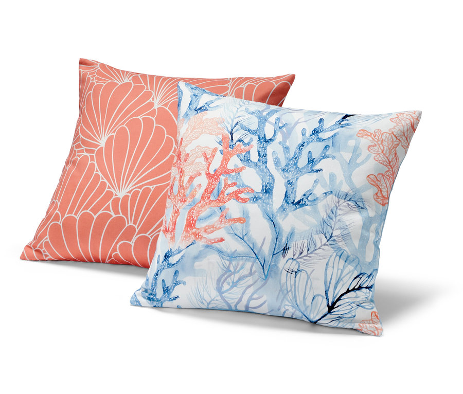 Két díszpárnahuzat: egy korall színű, fehér geometrikus mintával, a másik kék és korall színű korallokkal.