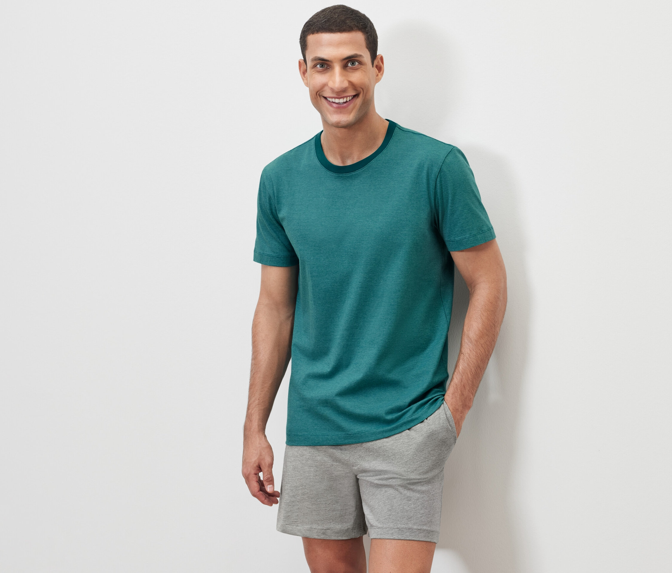 Férfi pózol fehér háttér előtt rövidnadrágos pizsamában.