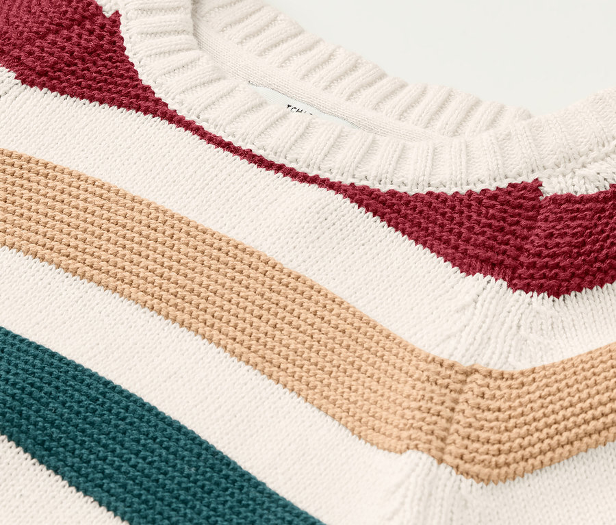 Közelkép egy színes csíkos kötött gyerekpulóverről.