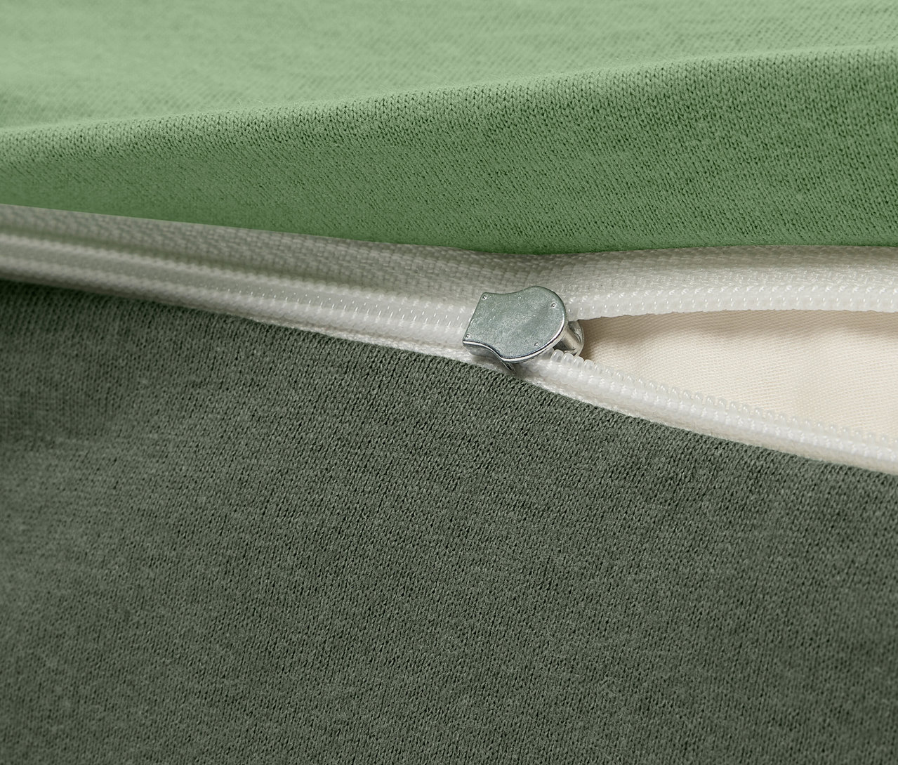 Egy zöld és szürke szövet huzat részlete cipzárral.