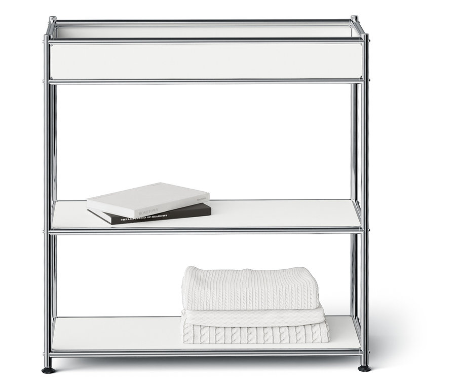 Króm polc három fehér polccal. A középső polcon két könyv, az alsó polcon fehér törölközők vannak egymásra rakva.