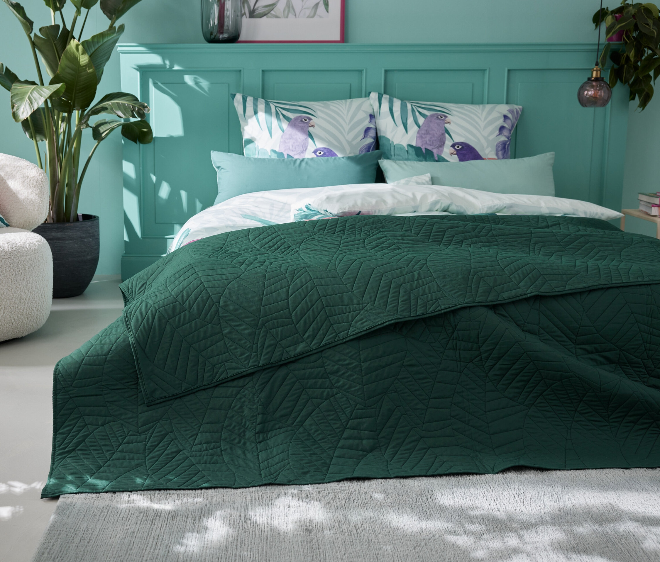 Egy zöld, steppelt ágytakaró (230 x 250 cm) fekszik egy ágyon egy hálószobában.