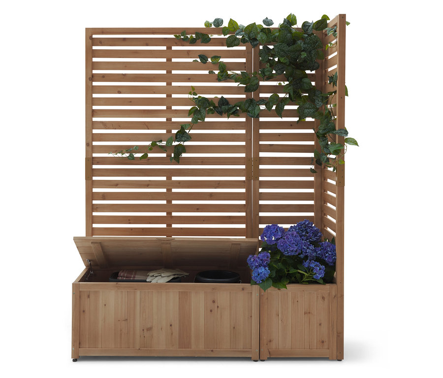 Fából készült szerkezet vízszintes lécekkel, részben borostyánnal benőve. Alatta nyitott fedelű fa láda áll.