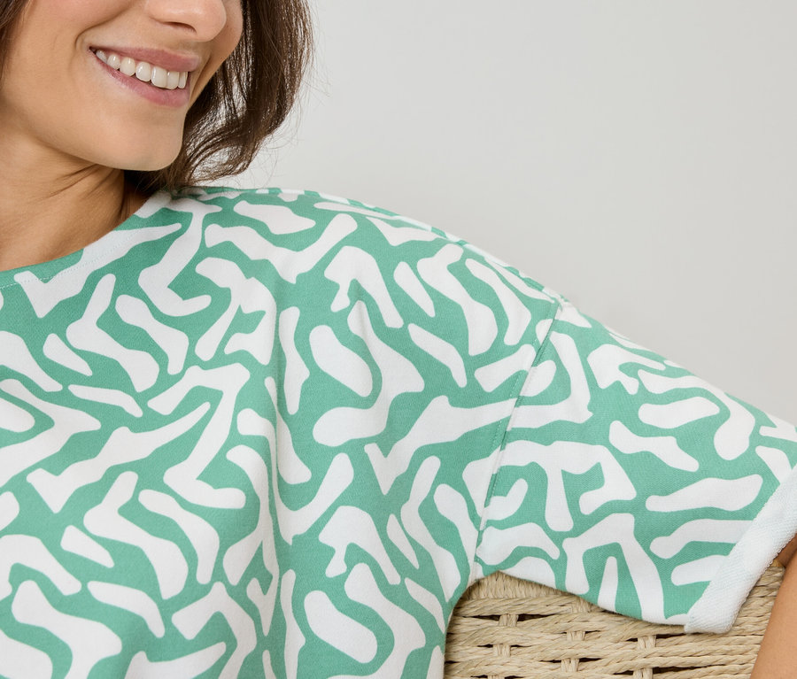 Nő visel egy zöld-fehér mintás felsőt.