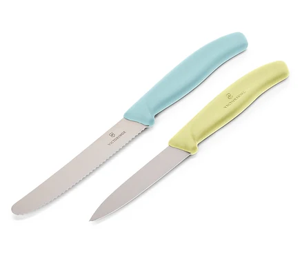 Két Victorinox kés fekszik átlósan egy fehér háttéren. A felső kés világoskék markolattal és recés pengével rendelkezik, az alsó kés világossárga markolattal és sima pengével.