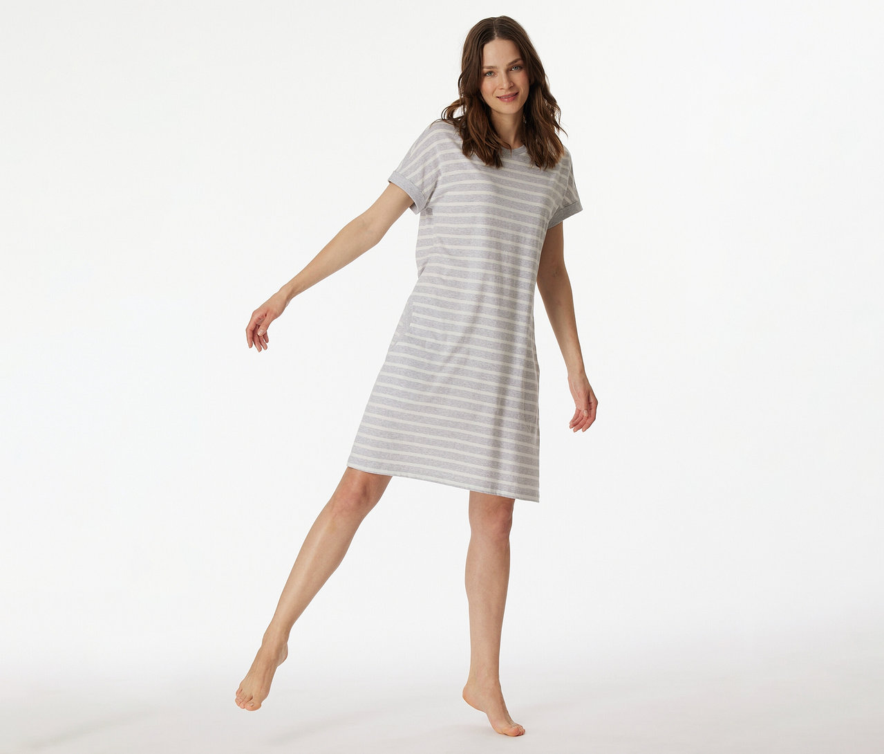 Csíkos SCHIESSER rövid ujjú hálóinget viselő nő, az egyik lábát felemeli.