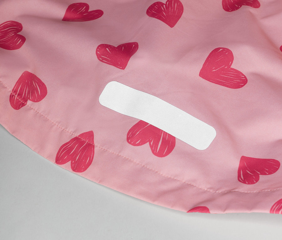 Egy rózsaszín, szívecskés mintázatú anyag és egy fehér címke közeli képe.