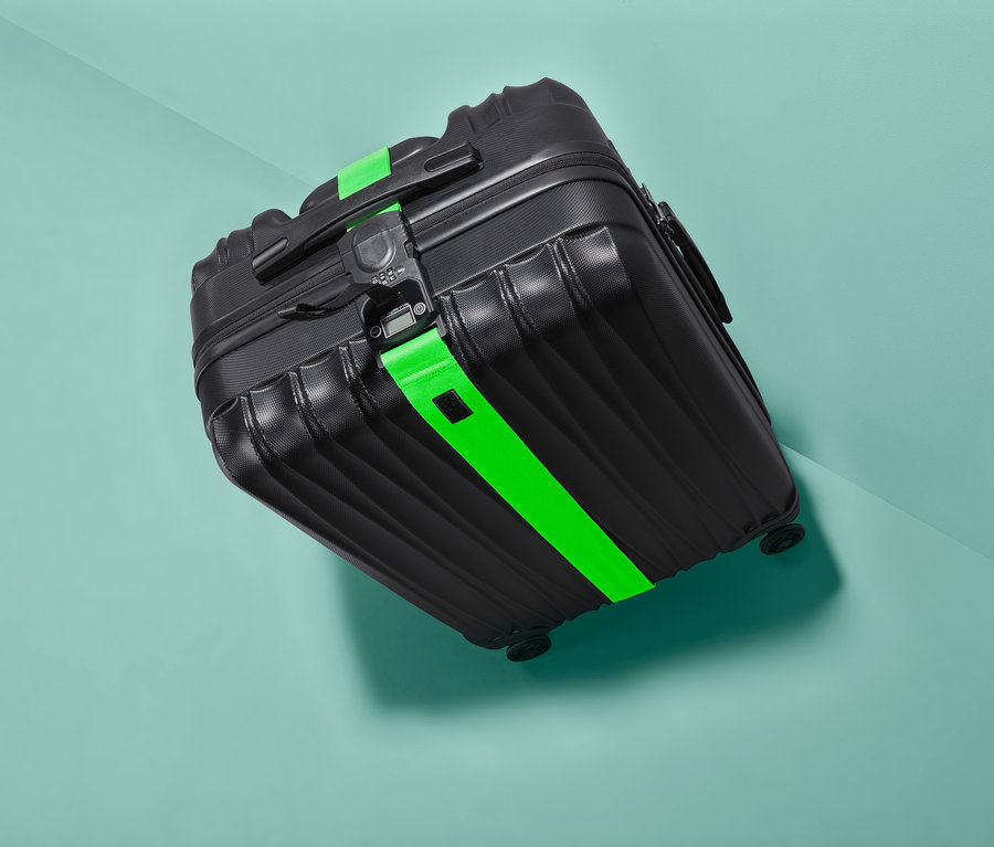 Fekete bőrönd zöld 3 az 1-ben bőröndpánttal.