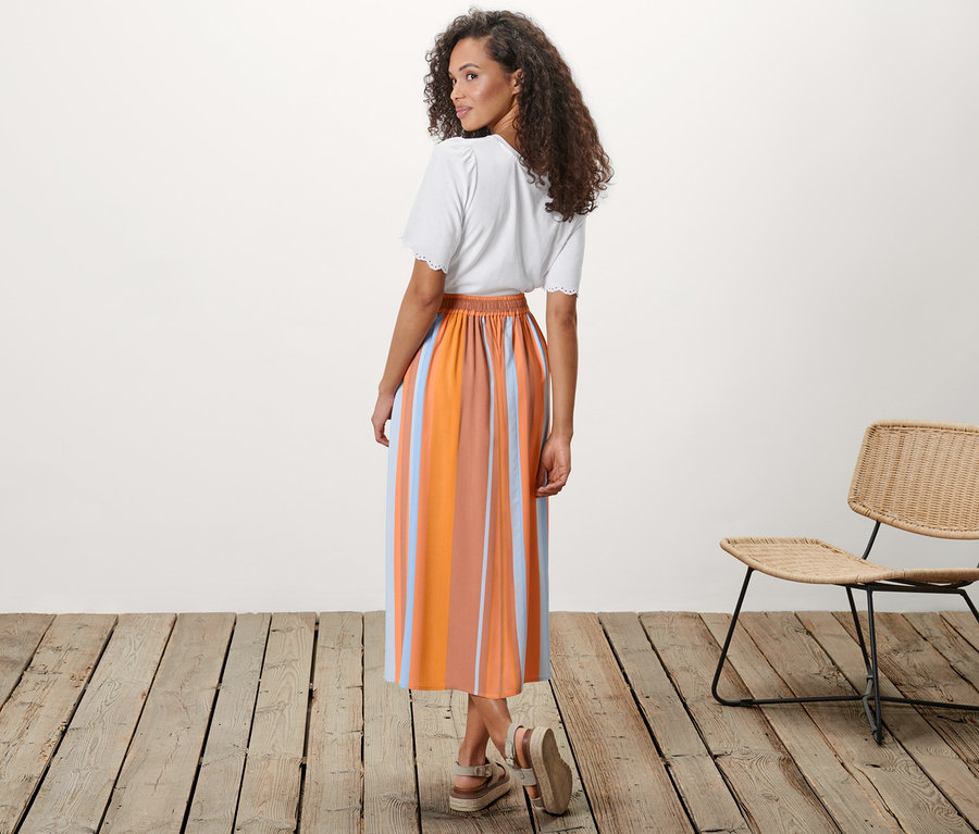 Nő pózol egy csíkos midi szoknyában.