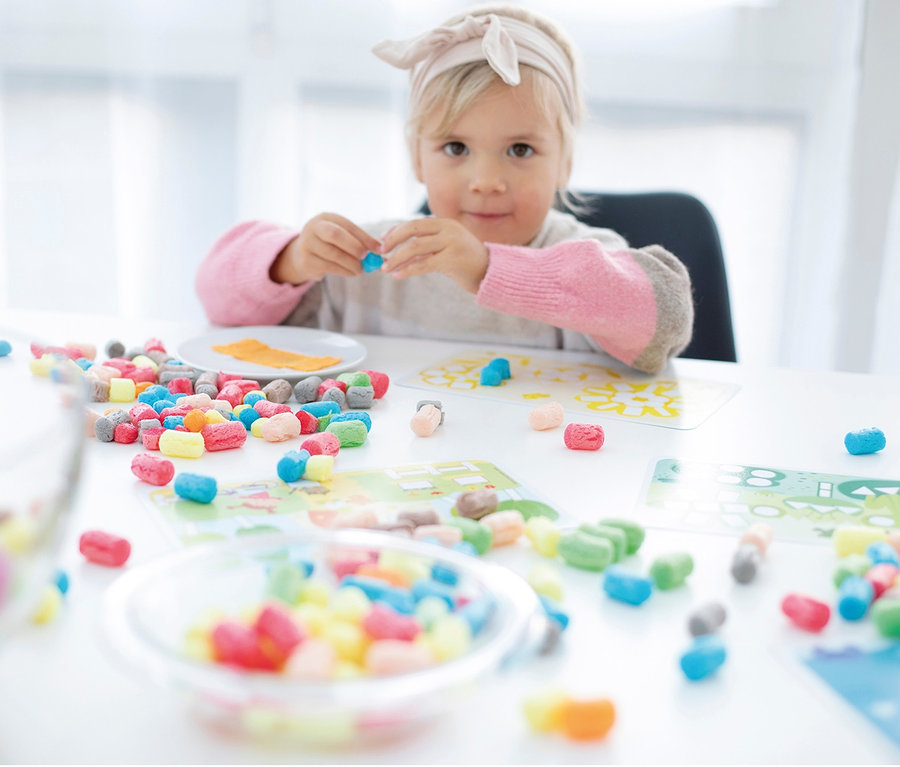 Kislány színes PlayMais®-Set, puffasztott kukorica játékkal játszik az asztalnál.