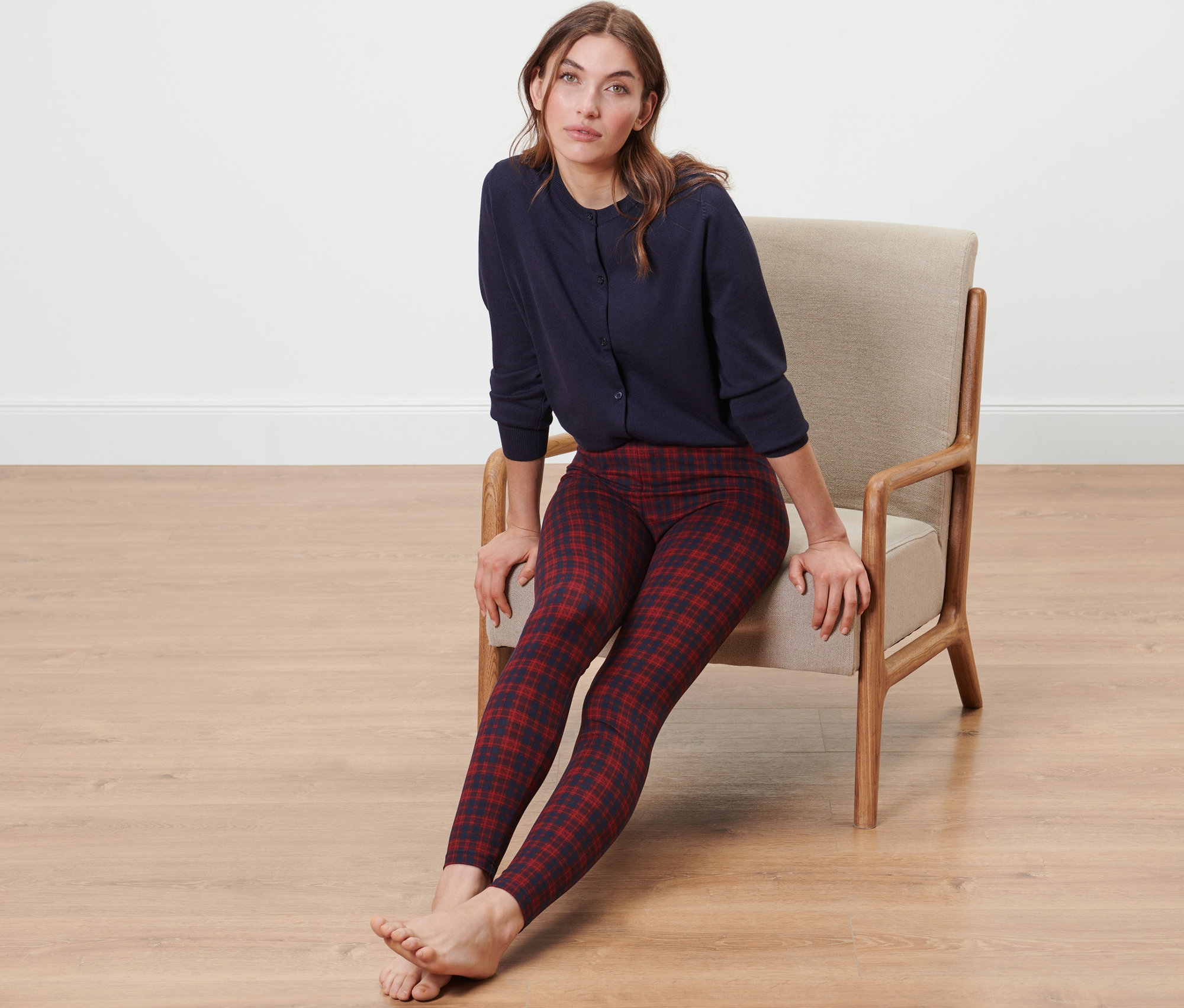 Egy nő ül egy székben, puha leggingset és egy kék felsőt visel.