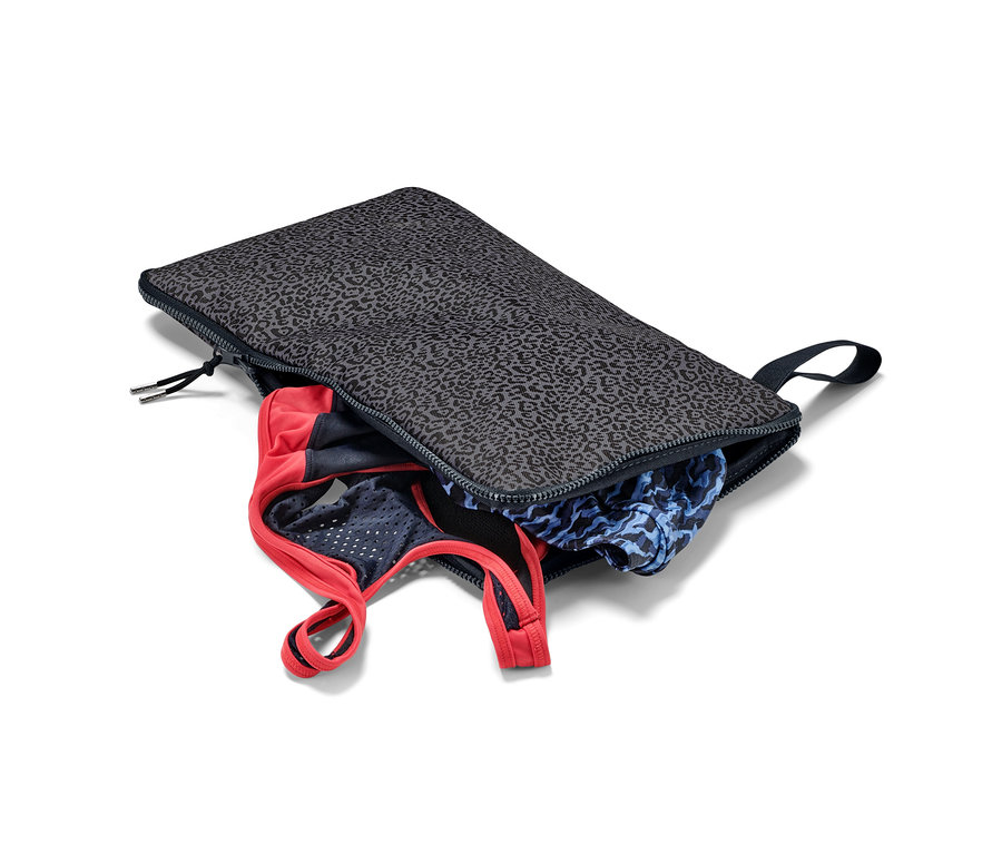 Egy nyitott 2 az 1-ben öltözőszőnyeg és vízhatlan táska ruhákkal.