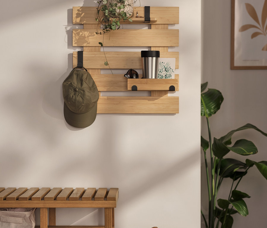 A falon egy fali polc lóg igény szerint használható akasztóval és aljjal. Rajta egy növény, egy termosz és egy képeslap található. Az egyik akasztón egy baseball sapka lóg.