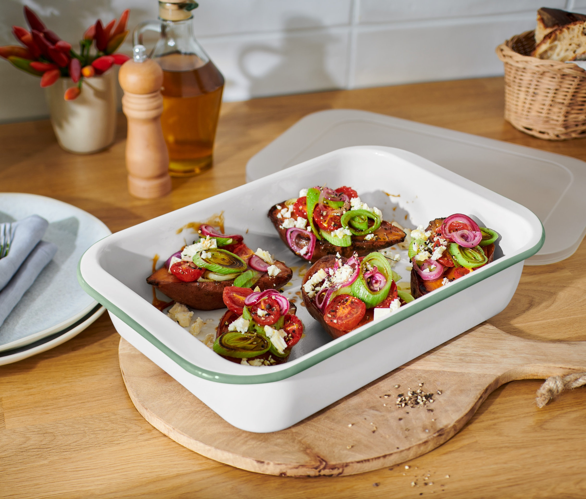 Sült édesburgonya paradicsommal, hagymával és fetasajttal, zománcozott sütőformában, fedővel.