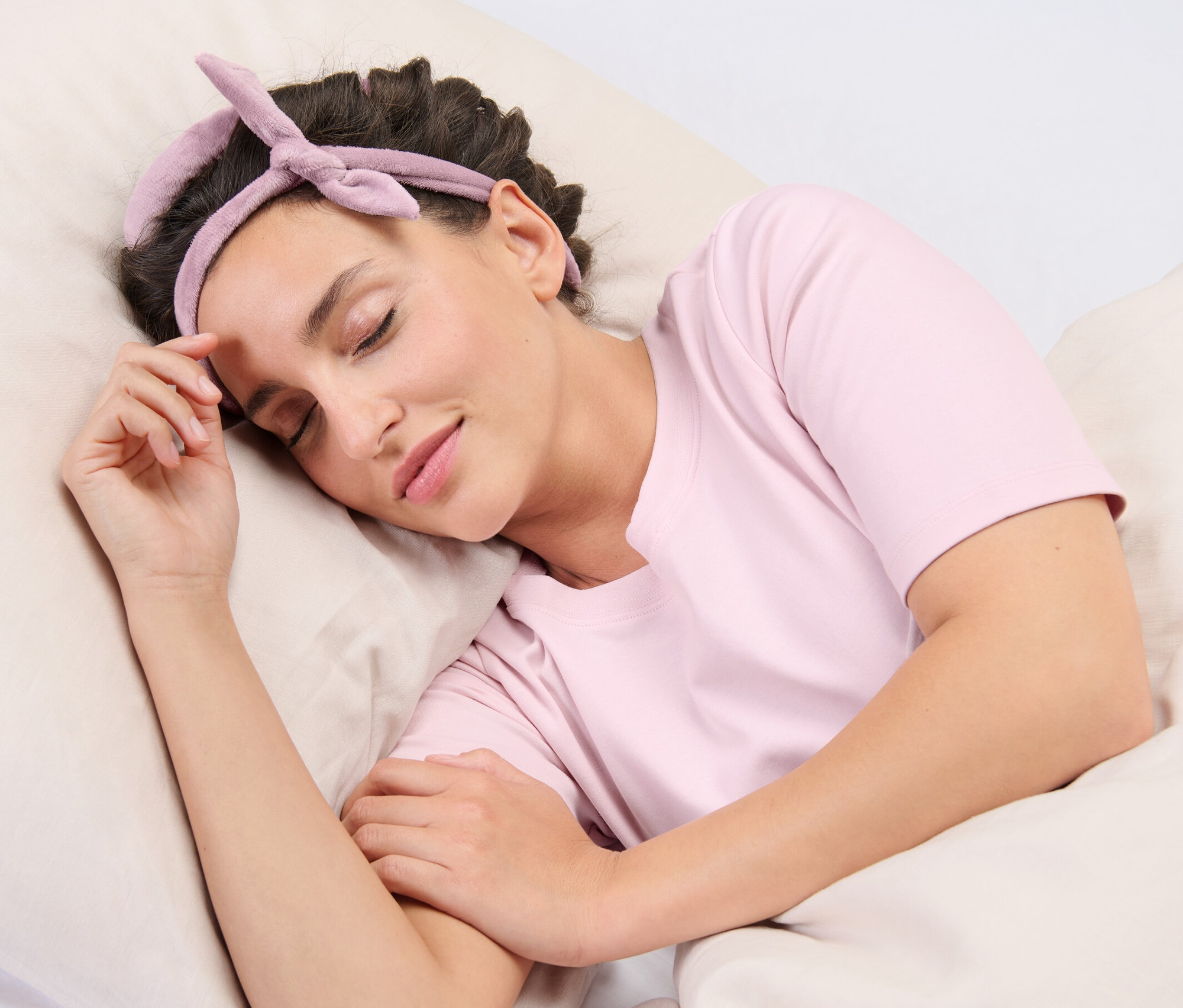 Egy nő alszik a párnán, és hőmentes hajgöndörítő készlet van a hajában.