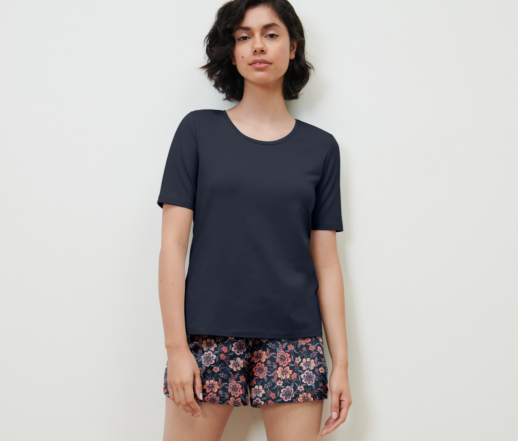 Nő virágos rövidnadrágos, sötétkék pizsamában.
