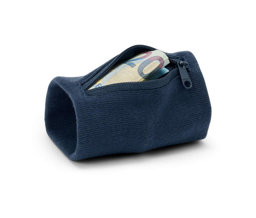 Egy sötétkék biztonsági pénztárca közeli képe, mely egy csuklópántra van rögzítve, és egy húsz eurós bankjegy van benne. A pénztárca fehér háttéren fekszik.