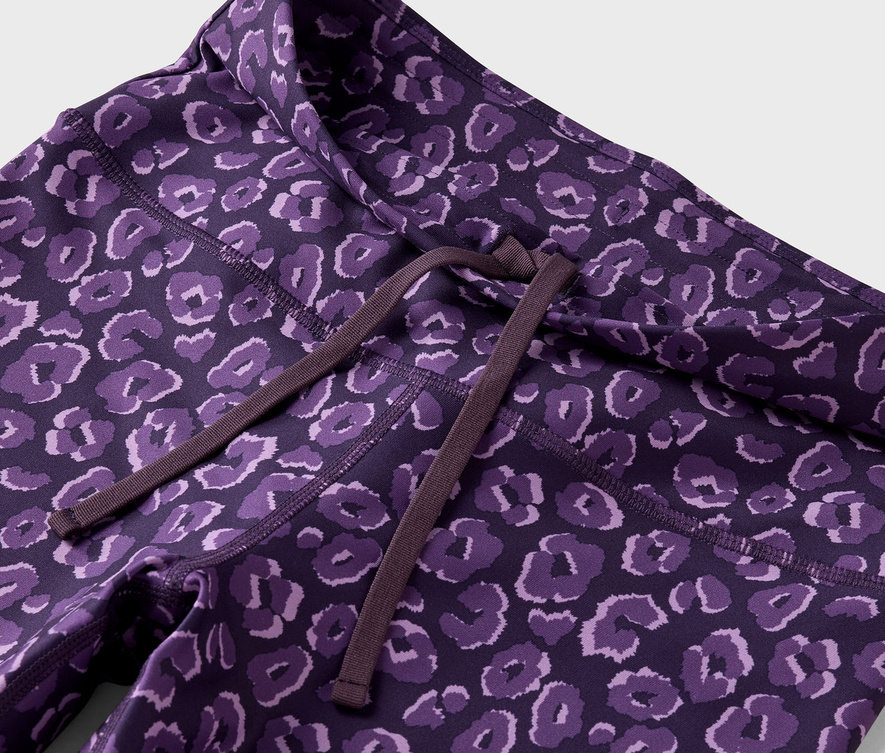 Lila leggings állatmintával és barna húzózsinórral a derékrészen.