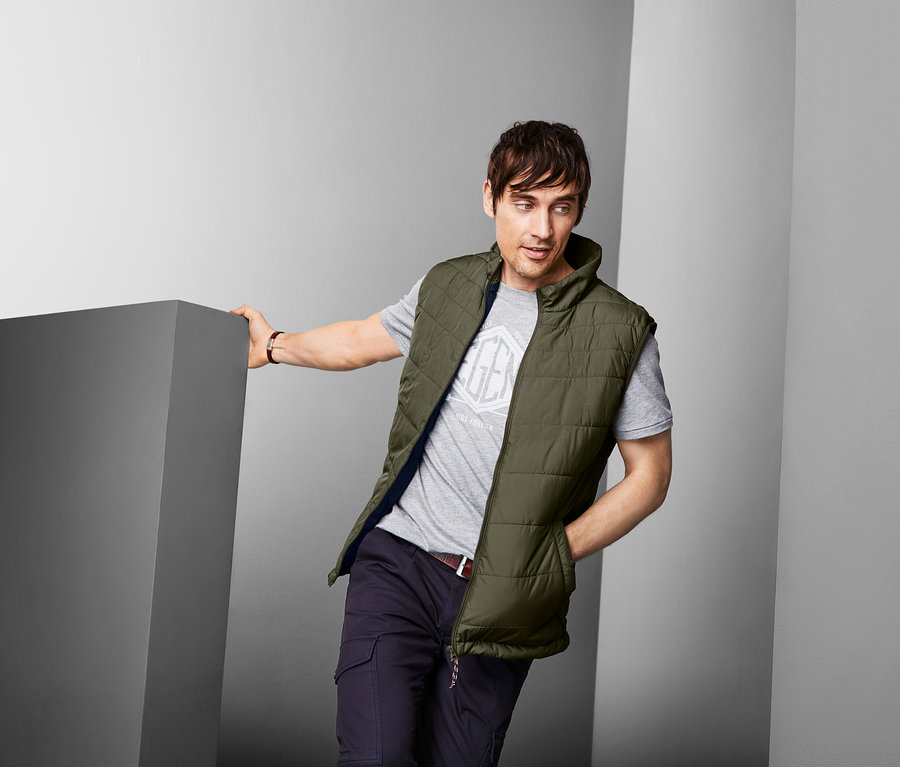 Férfi steppelt mellényben pózol.