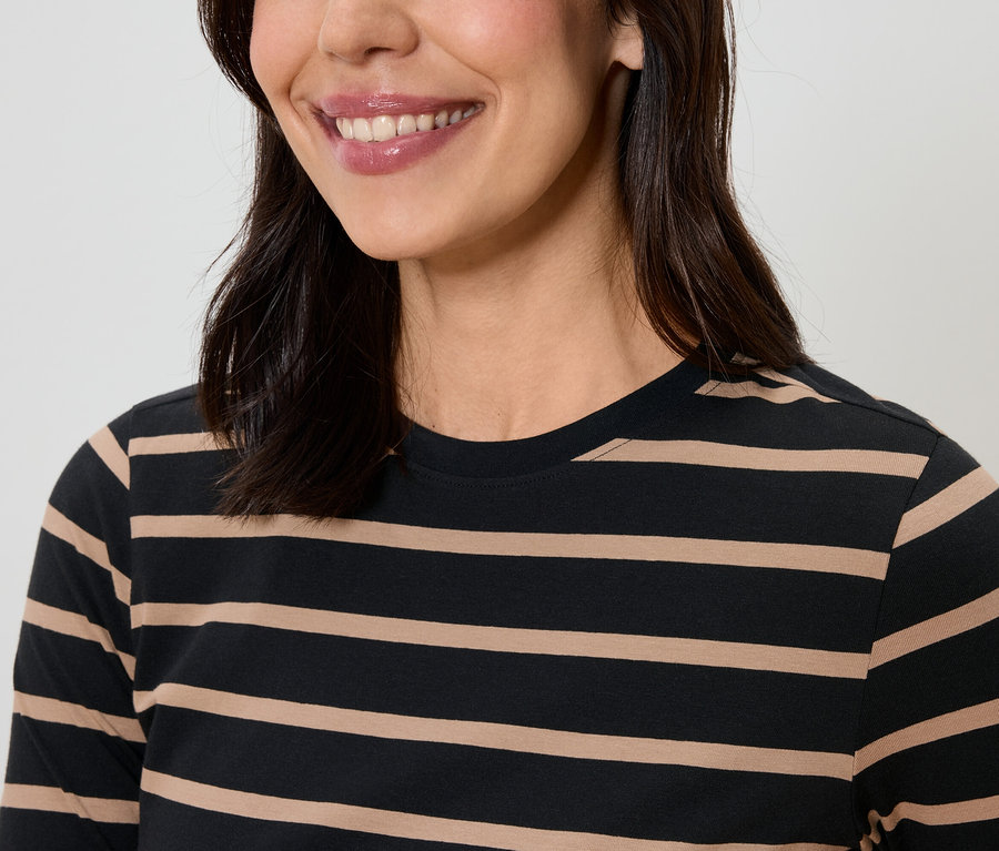 Mosolygó, sötét hajú nő csíkos pólót visel.