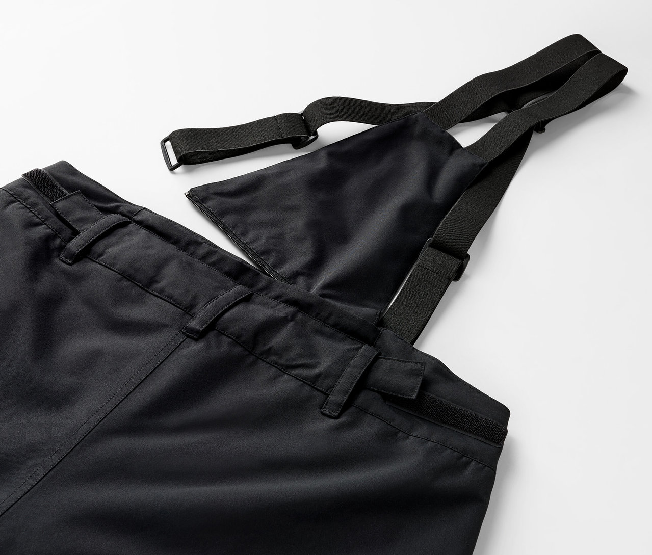 Egy fekete kantáros nadrág részlete, rugalmas pántokkal.