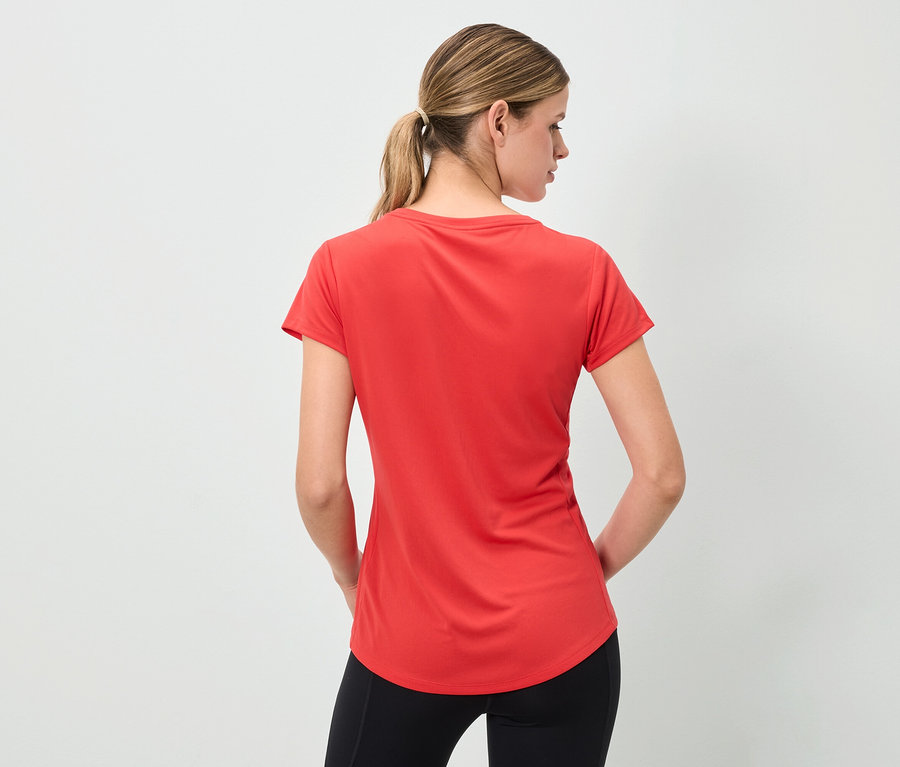 Hátulról látható nő piros pólót és fekete leggingset visel.