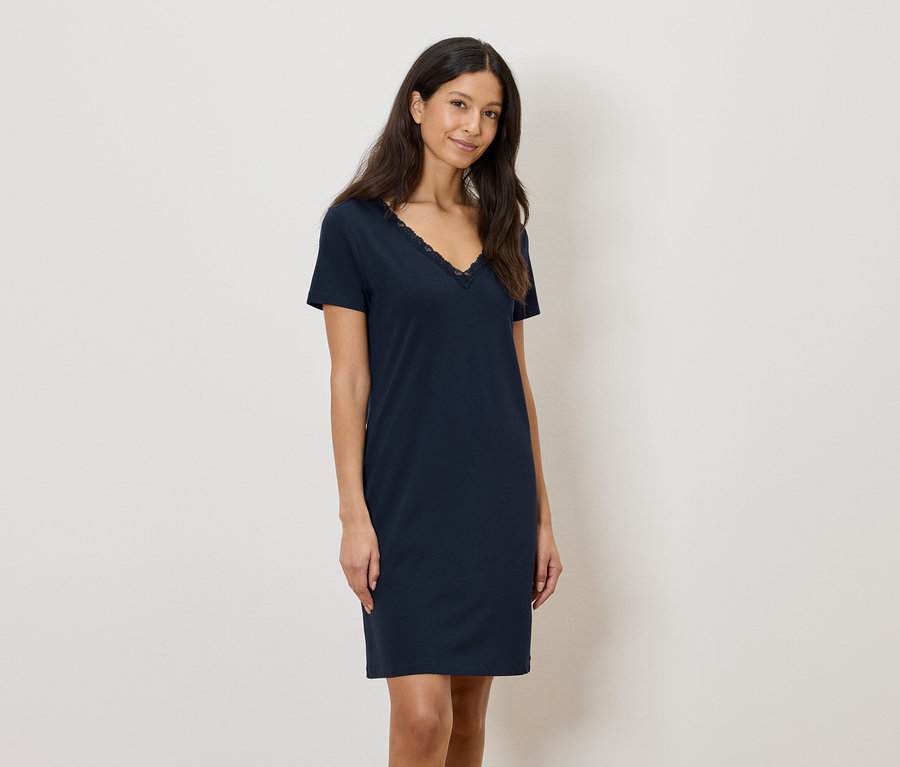 Nő visel egy sötétkék, térdig érő ruhát, csipkés díszítéssel a V-nyakánál.