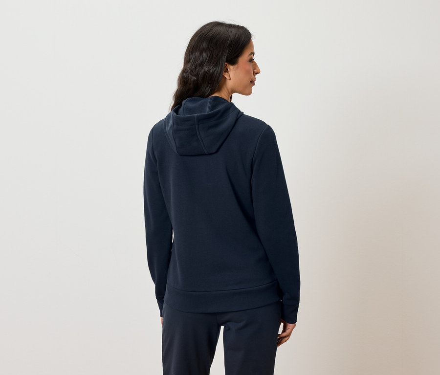 Nő hátulról sötétkék kapucnis pulóvert és jogging nadrágot visel.