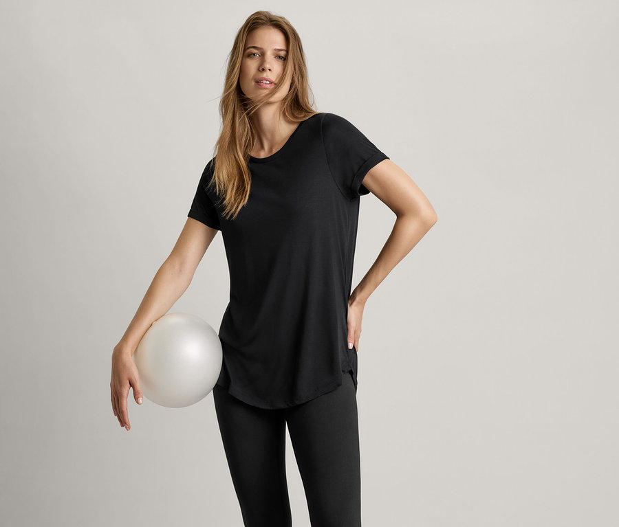 Nő labdát tart és fekete hosszú felsőt visel.