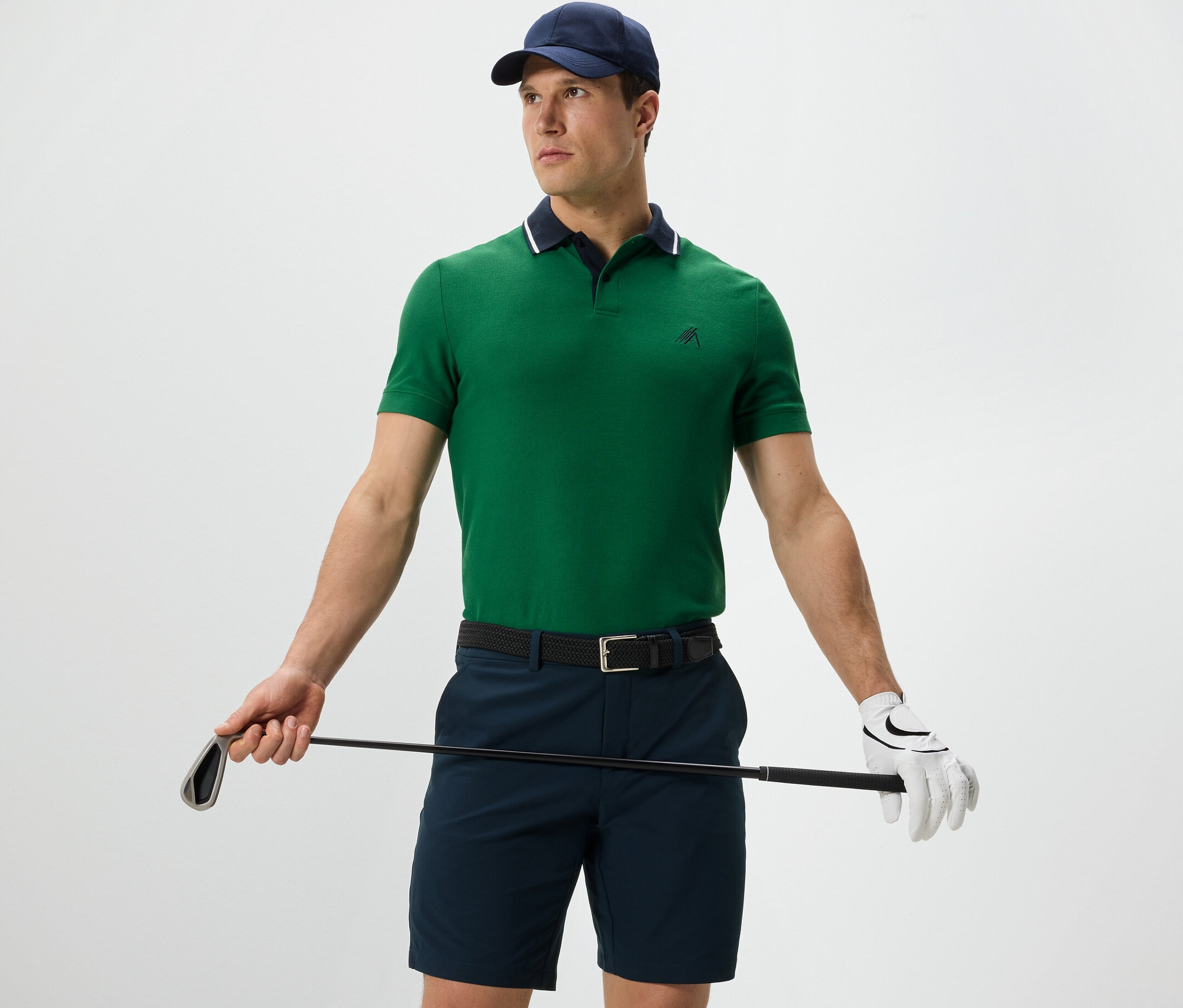 Férfi golfütőt tart, és zöld funkcionális pólót visel.