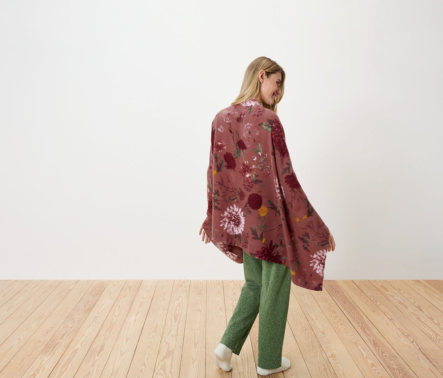 Egy nő a válla fölött néz hátra virágos kendőben és zöld nadrágban.