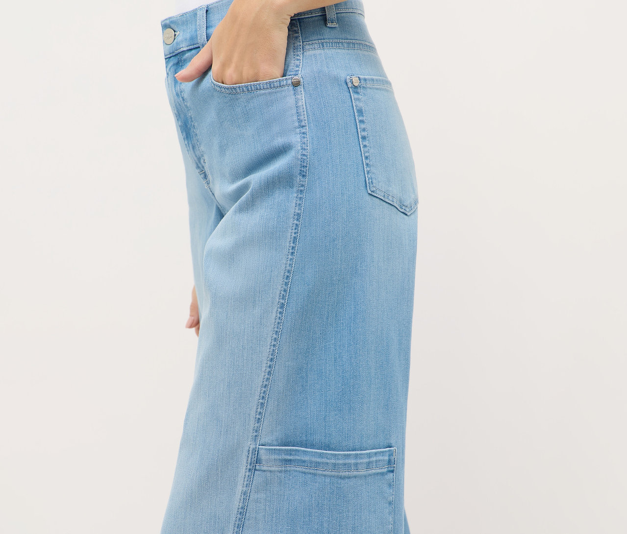 Egy személy közeli képe, aki Angels Denim »Liva« bőszárú cargo farmernadrágot visel, és a kezét a zsebében tartja.