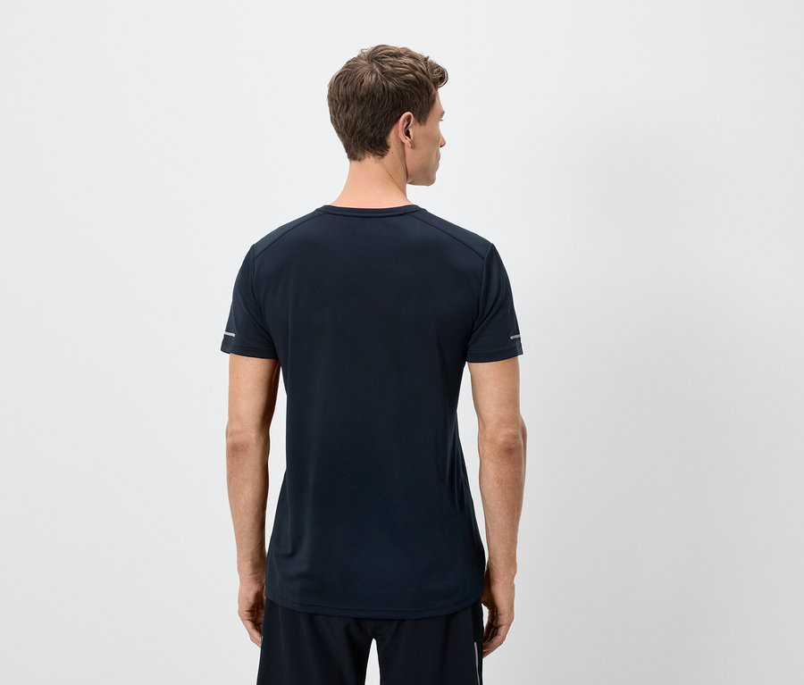 Egy férfi hátulról egy sötétkék pólót és fekete rövidnadrágot visel fehér háttér előtt.