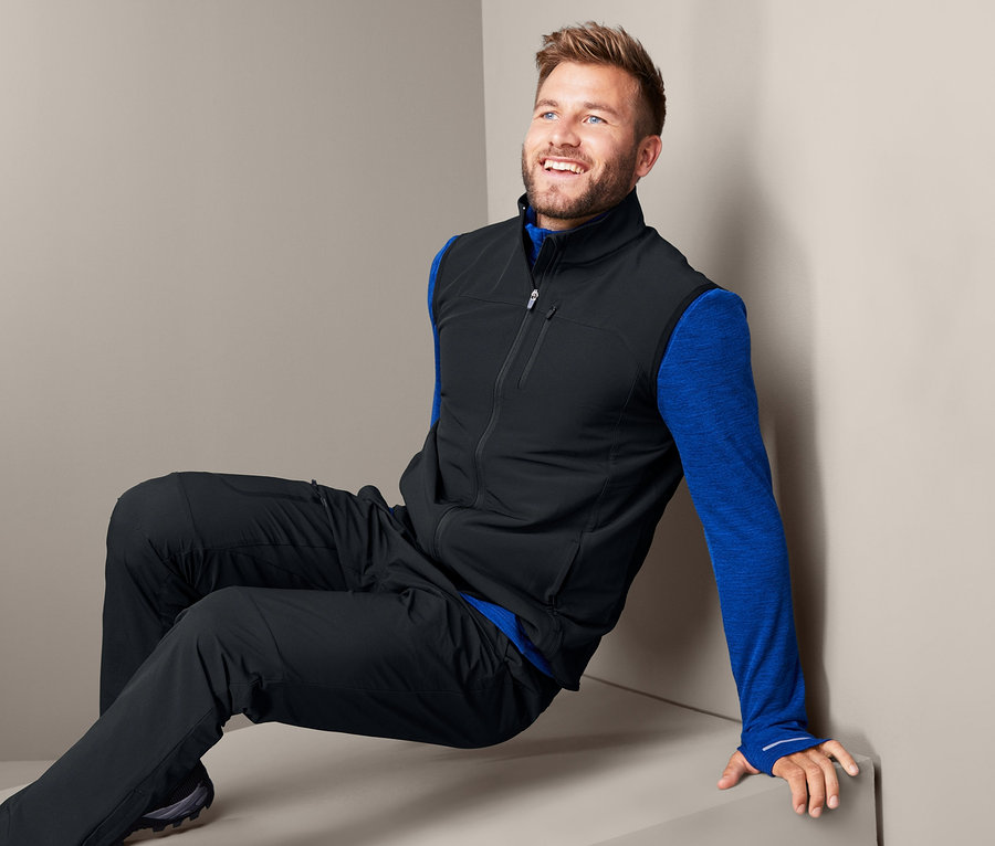 Férfi ül és fekete softshell mellényt visel.