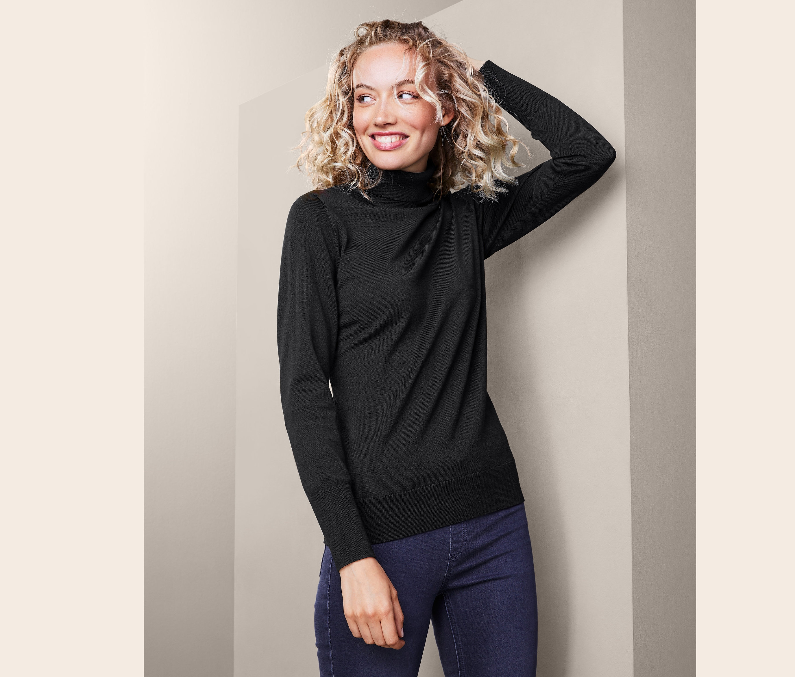 Nő szőke, göndör hajjal, fekete garbó felsőben.