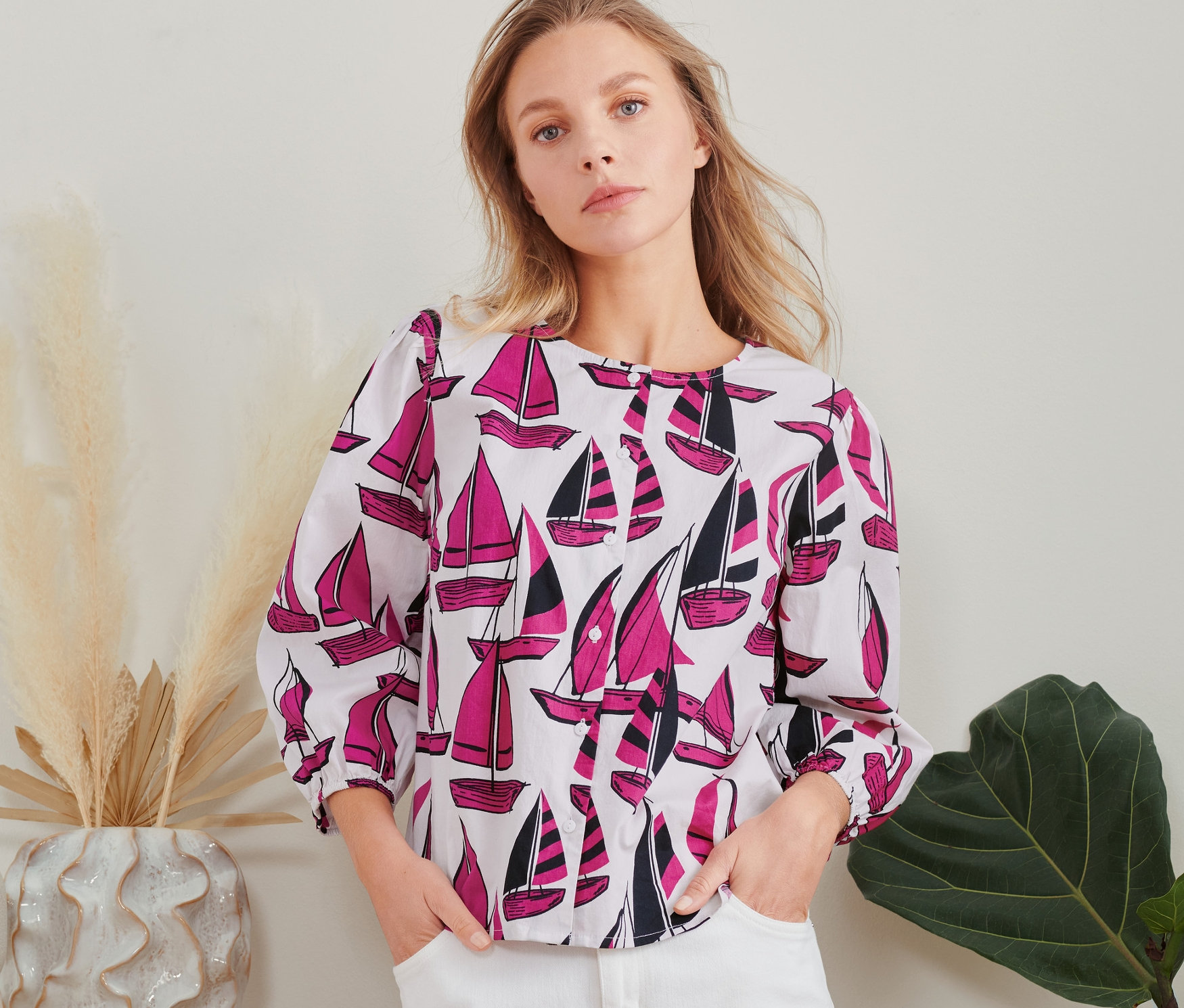 Nő pózol vitorlás mintás blúzban.
