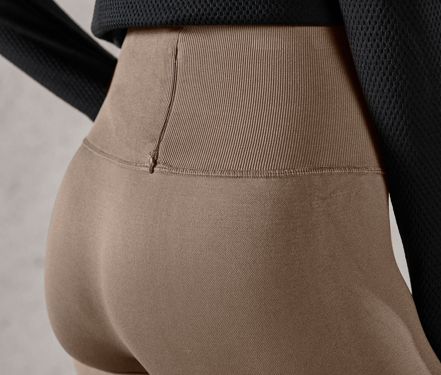 Egy nő részlete, aki barna színű, női seamless futónadrágot visel.