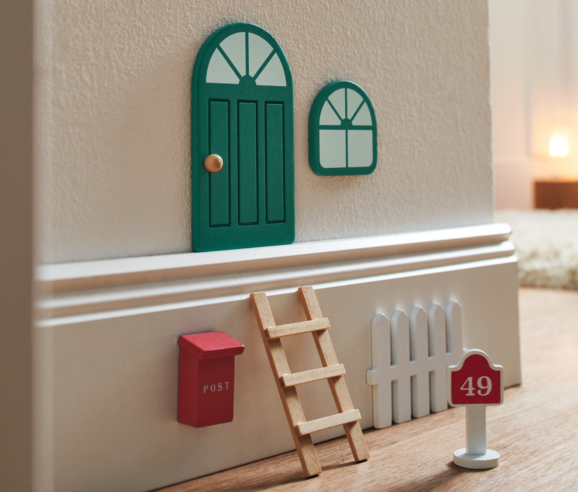 Egy Manóajtó készlet zárt zöld ajtóval és ablakkal, piros postaládával, létrával és fehér kerítéssel, a házszáma 49.