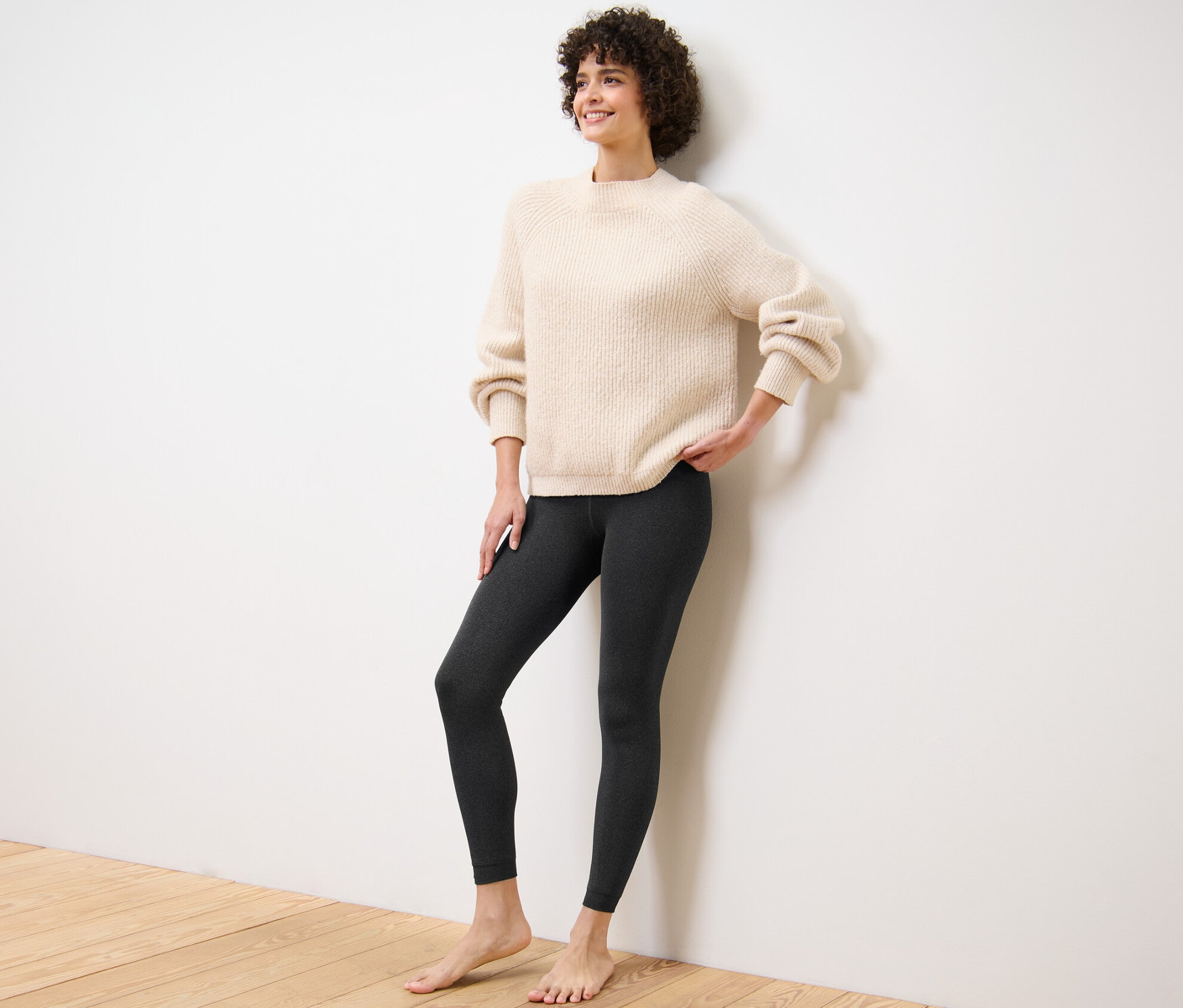 Nő pózol plüssbéléses leggingsben és pulóverben.