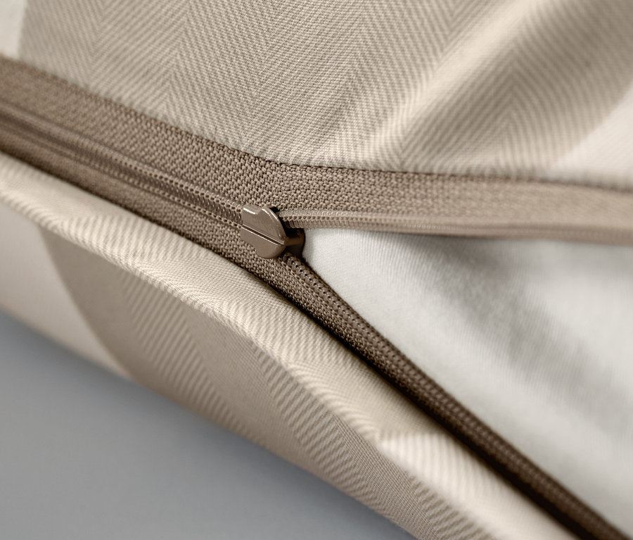 Egy bézs színű párnahuzat cipzárral, közeli felvételen.