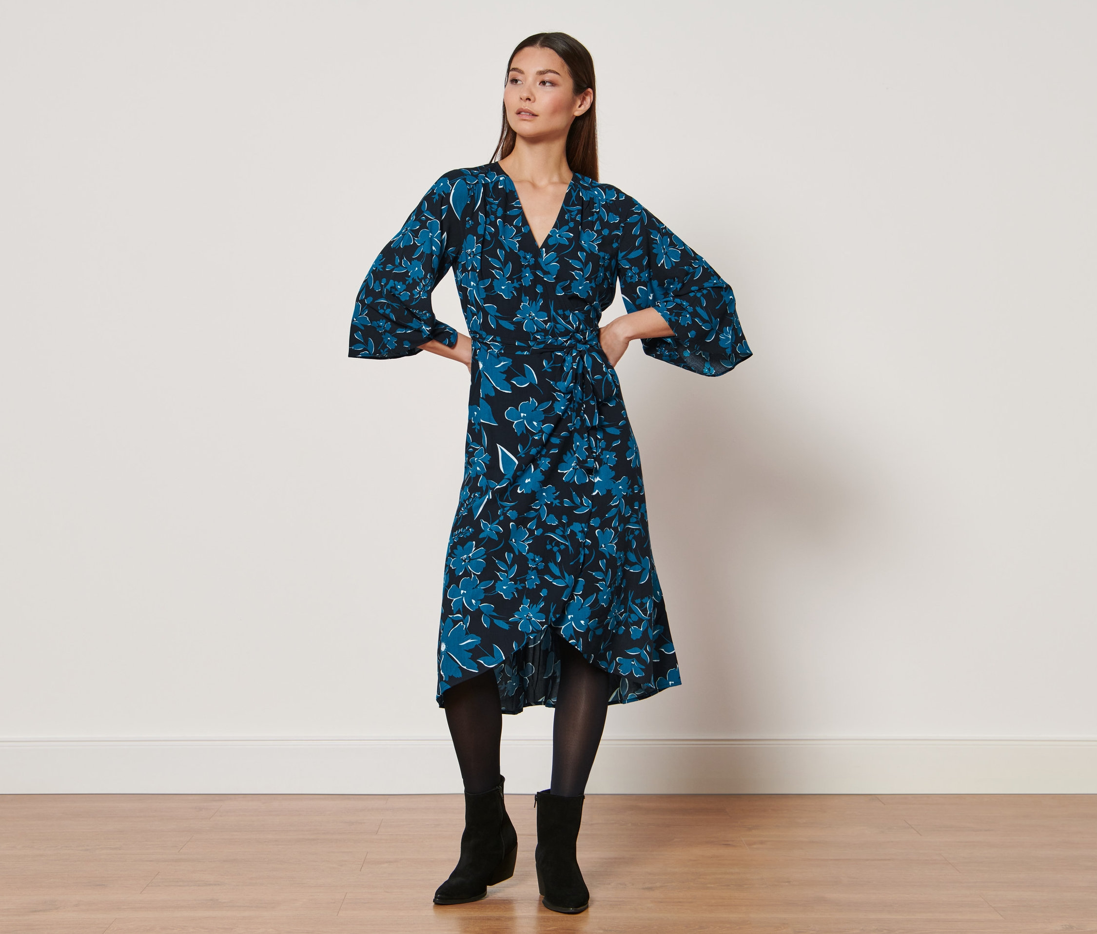 Nő pózol egy mintás ruhában.